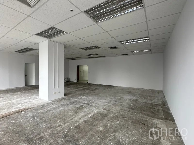 Office Space for rent in Watthana, Bangkok - Open workspace with a central column and fluorescent lighting.