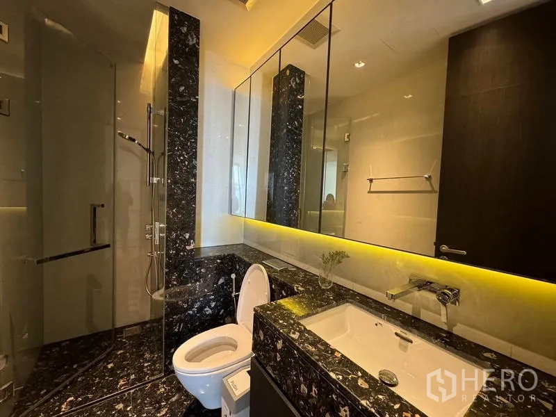 Condominium for rent - Marble bathroom with glass shower, wide mirror, and underlit vanity.