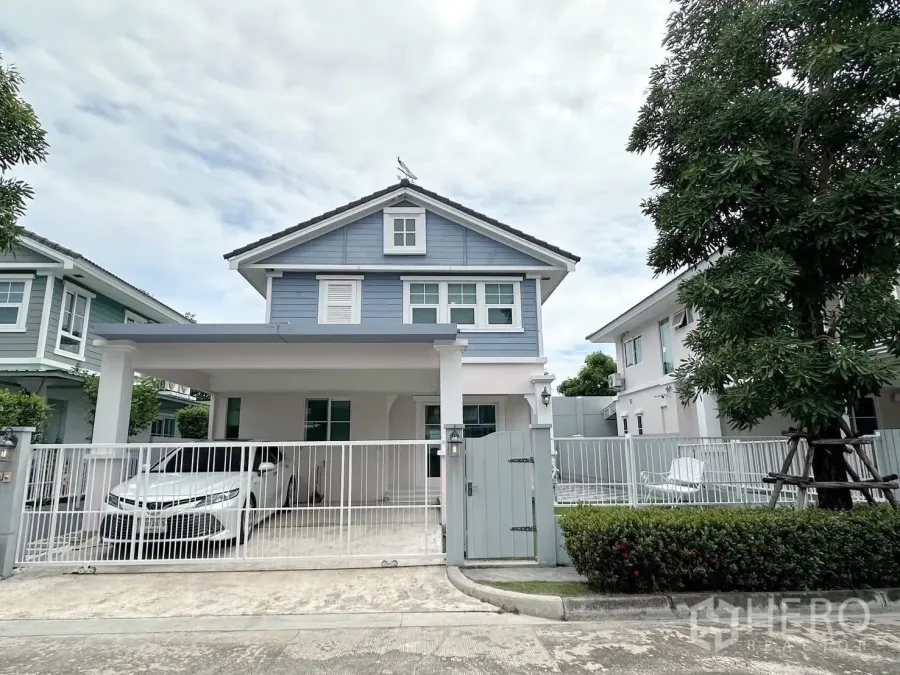 Detached House for rent or sale in Bang Phli, Samut Prakan - Front view of a two-storey blue detached house with gated driveway and covered carport.