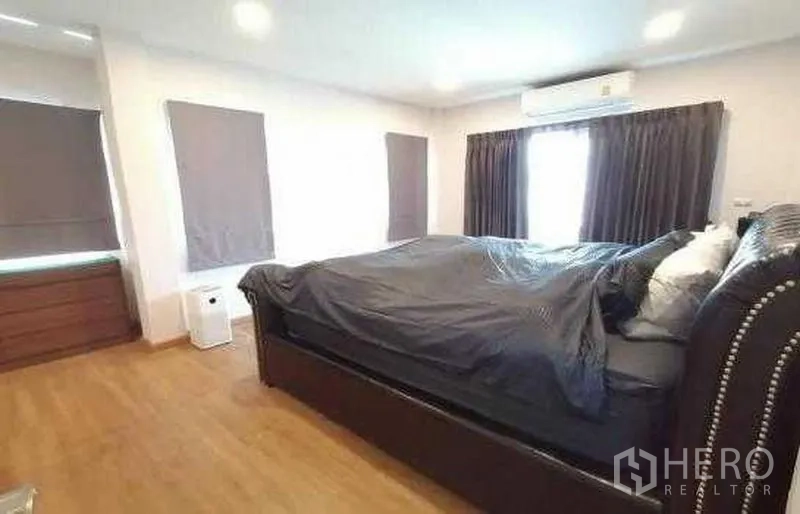 Detached House for sale in Bang Phli, Samut Prakan - Spacious master bedroom with king bed, wood floors, blackout curtains and air conditioner in a detached house in Bang Phli, Samut Prakan.