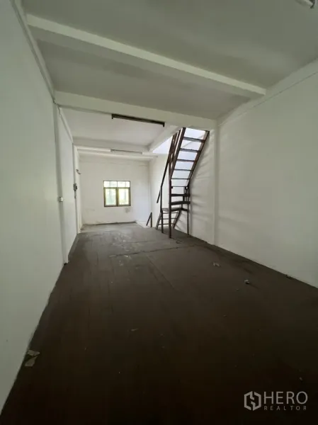 Shophouse for rent in Khlong Toei, Bangkok - Upper level room with dark wooden floor, white walls, small end window and an internal metal staircase.