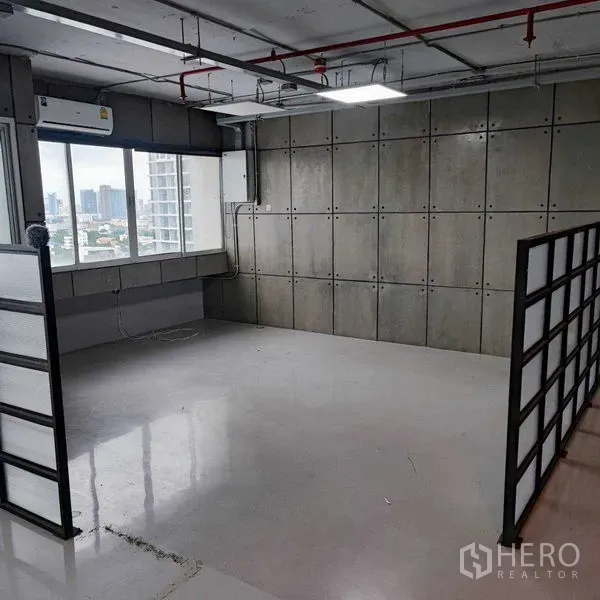 Office Space for rent in Watthana, Bangkok - Corner workspace featuring city-view windows, concrete panel wall, air conditioner and a partial partition.