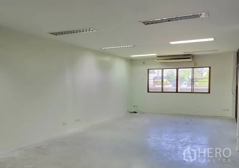 Warehouse for rent in Sam Phran, Nakhon Pathom - Open office space with window, split-type air conditioner and overhead lights.