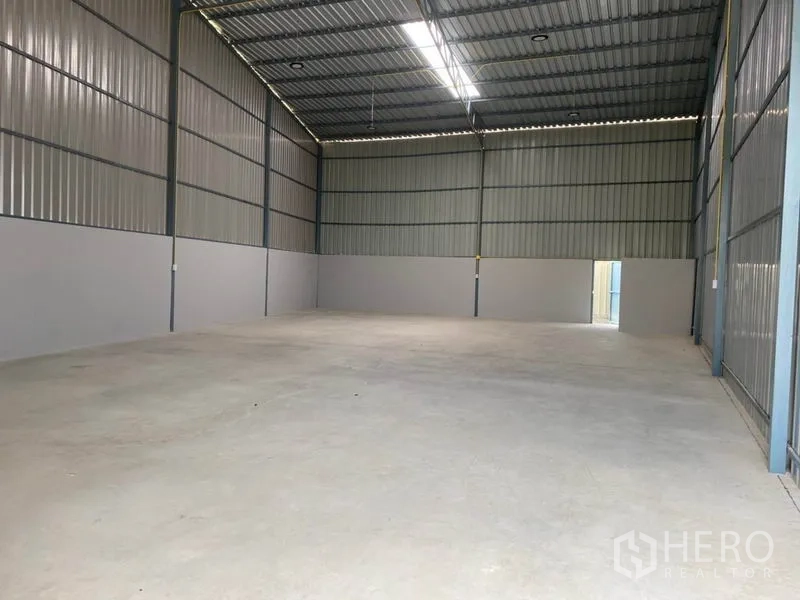 Warehouse for rent in Bang Yai, Nonthaburi - Open 200 sqm warehouse space with tall steel walls, bright lighting, and level concrete floor.