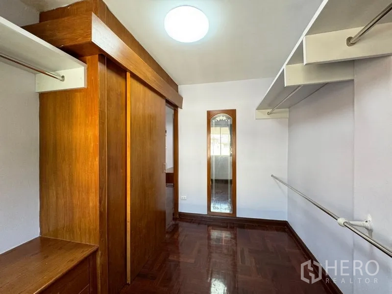 Townhouse for rent or sale in Suan Luang, Bangkok - Walk-in closet with wooden wardrobes, open shelves and full-height mirror