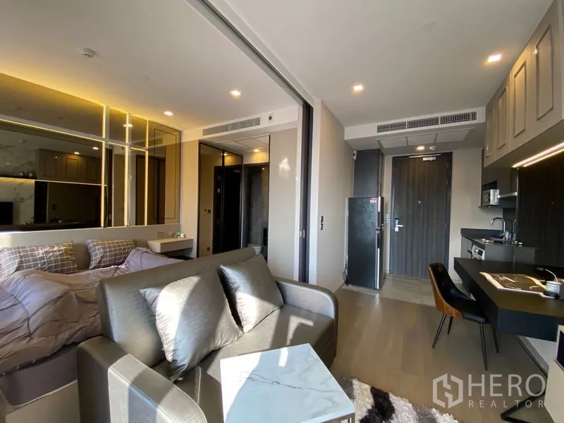 Condominium for rent in Watthana, Bangkok - Entry hall kitchenette with built-in cabinets, fridge and washer, adjacent to the living area and bedroom via sliding glass partition.