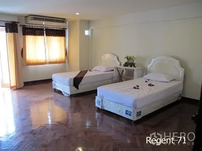 Townhouse for rent in Khlong Toei, Bangkok - Guest bedroom with twin beds, parquet floors, and large windows providing daylight.