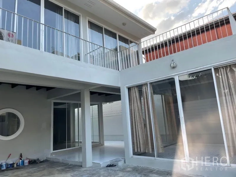 Detached House for rent in Huai Khwang, Bangkok - Front courtyard view showing large sliding glass doors and upper balcony railings of the home.