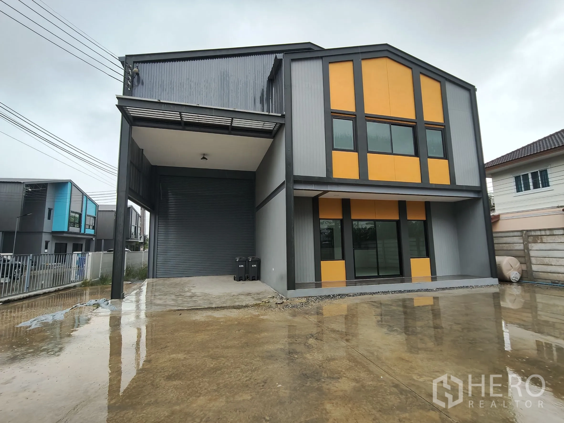 Warehouse for rent or sale in Bang Yai, Nonthaburi - Modern warehouse exterior in grey and orange with two‑storey office, covered loading bay, large roller shutter and concrete yard.