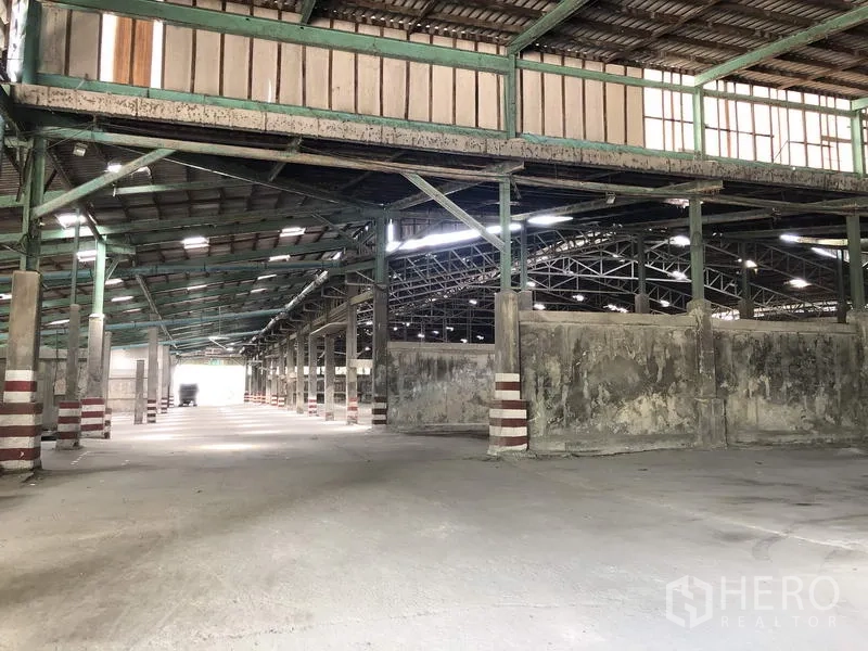 Warehouse for rent in Thanyaburi, Pathum Thani - Warehouse section with a small mezzanine, concrete partitions and multiple loading bays.