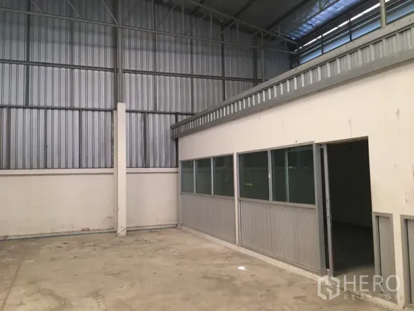 Warehouse for rent in Suan Luang, Bangkok - Concrete floor storage area with metal cladding walls and side windows.