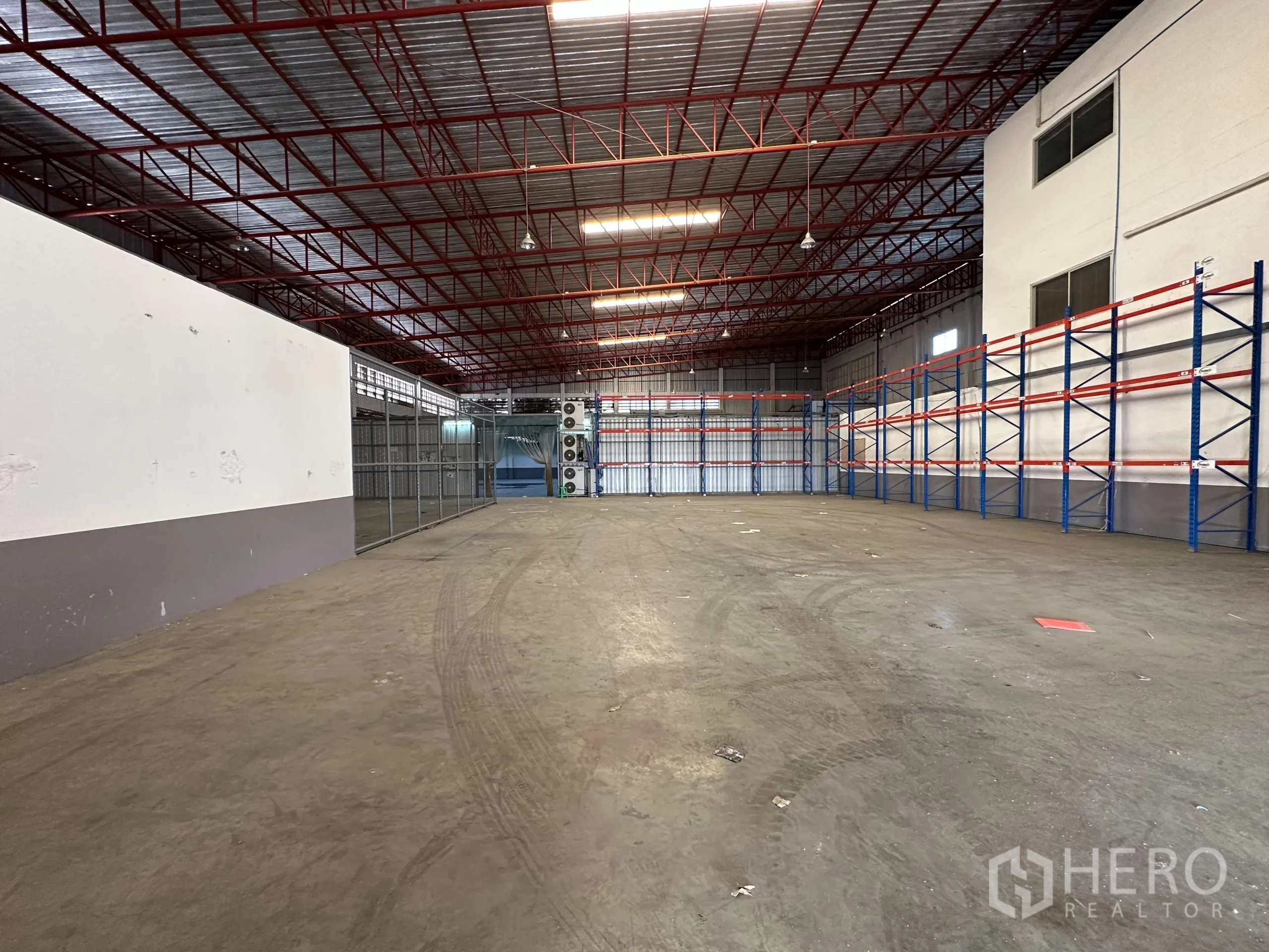 Factory for rent - Open warehouse space with pallet racking and fenced storage section.