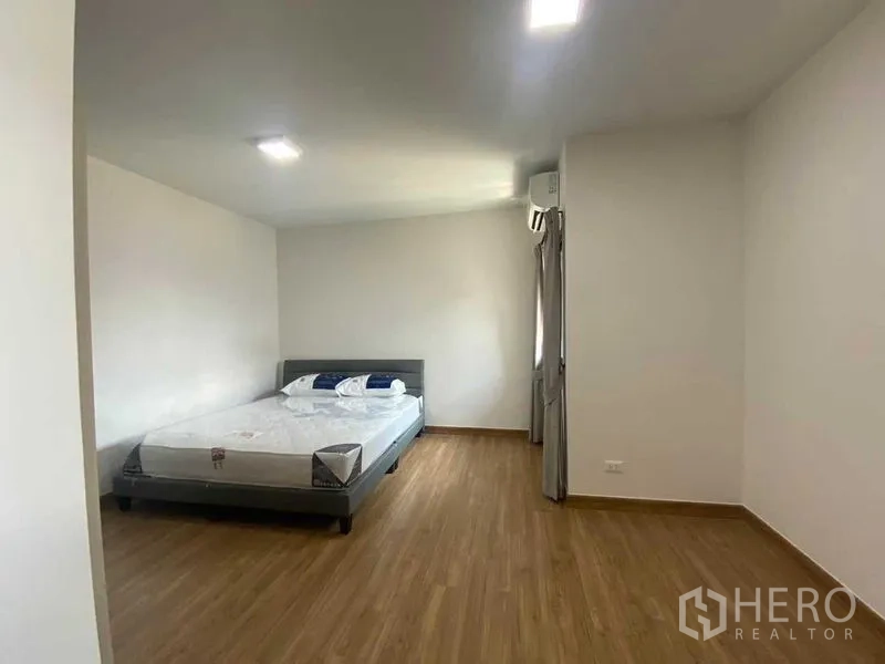 Detached House for rent in Khan Na Yao, Bangkok - Minimalist bedroom with double bed, wood floor and air conditioner.