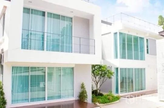 Townhouse for rent in Khlong Toei, Bangkok - Modern white townhouse facade with floor-to-ceiling glass and a small landscaped courtyard in Bangkok.