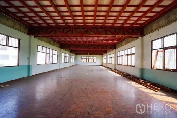 Retail Space for rent in Watthana, Bangkok - Spacious open-plan retail floor with parquet flooring, red truss ceiling, and rows of windows providing natural light.