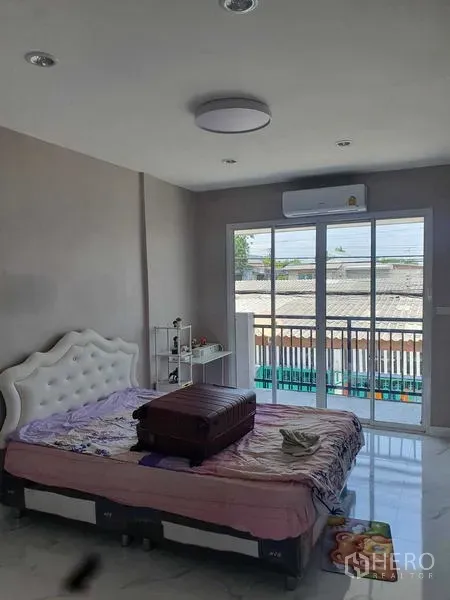 Home Office for rent in Suan Luang, Bangkok - Bright bedroom with sliding glass doors to a balcony and a wall-mounted air conditioner.