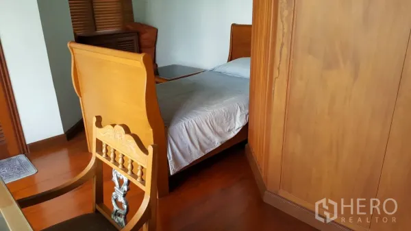 Detached House for rent in Khlong Toei, Bangkok - Secondary bedroom with single wooden bed, wardrobe and polished hardwood floors.