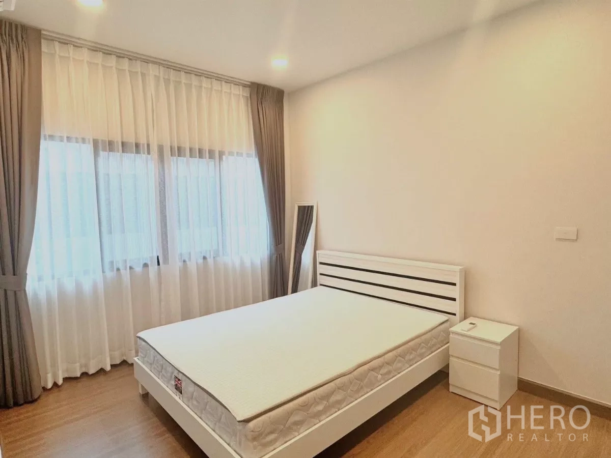 Detached House for rent in Bang Phli, Samut Prakan - Guest bedroom with large windows, white bedframe and bedside table.