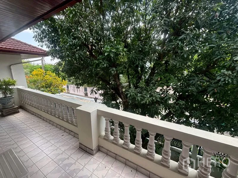 Detached House for sale in Suan Luang, Bangkok - Shaded tiled balcony with white balustrade overlooking mature trees.