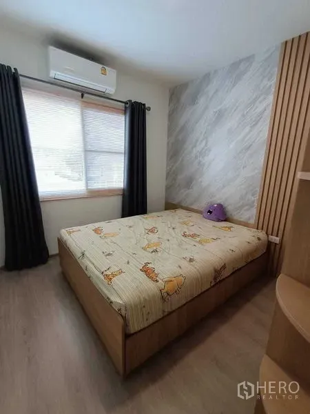Townhouse for rent in Prawet, Bangkok - Bedroom featuring a wood-panel accent wall, built-in shelving and an air conditioner.