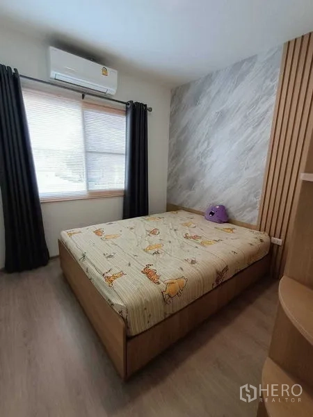 Townhouse for rent in Prawet, Bangkok - Bedroom featuring a wood-panel accent wall, built-in shelving and an air conditioner.
