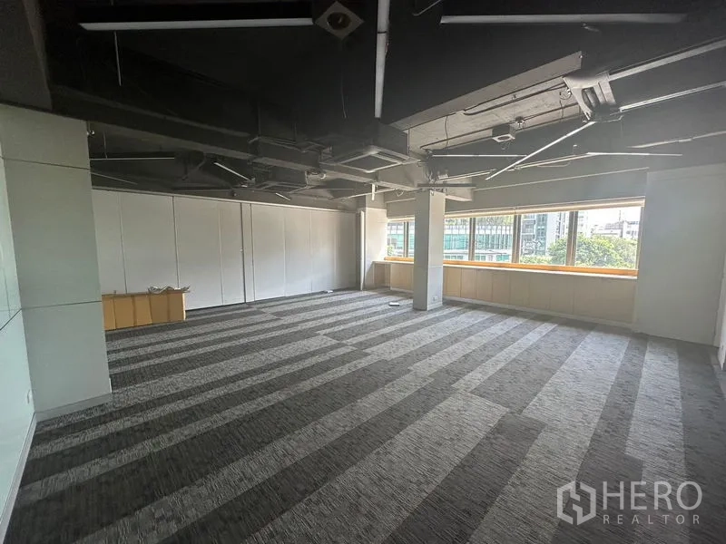 Office Space for rent in Khlong Toei, Bangkok - Corner office area with large windows, city and greenery views, and exposed ducting.