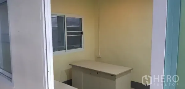 Warehouse for rent in Bang Phli, Samut Prakan - Compact office cabin with sliding window and storage desk inside the warehouse.