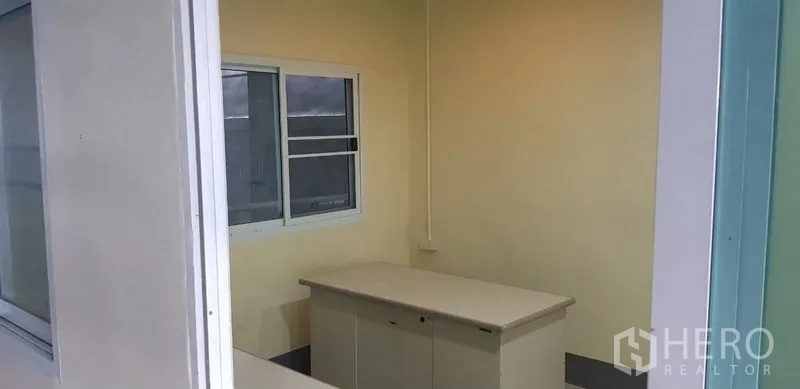 Warehouse for rent in Bang Phli, Samut Prakan - Compact office cabin with sliding window and storage desk inside the warehouse.