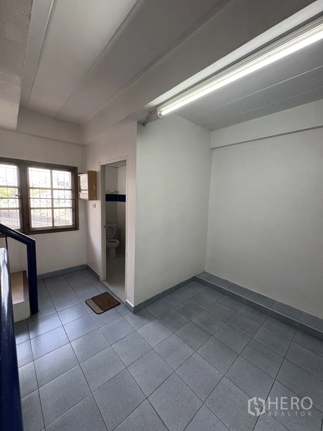 Shophouse for rent in Phra Khanong, Bangkok - Stair landing with window and a door to a restroom.
