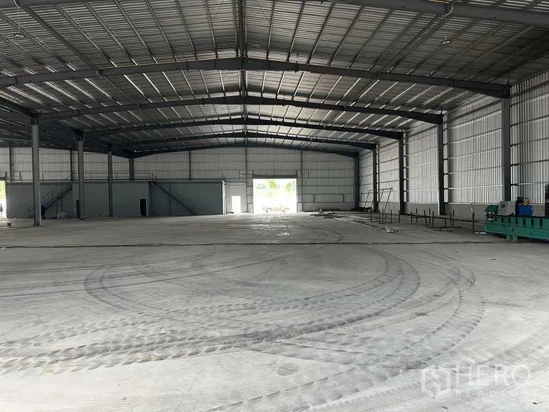 Factory for rent in Rayong - Large factory hall with smooth concrete floor, rear roller door and internal office block.