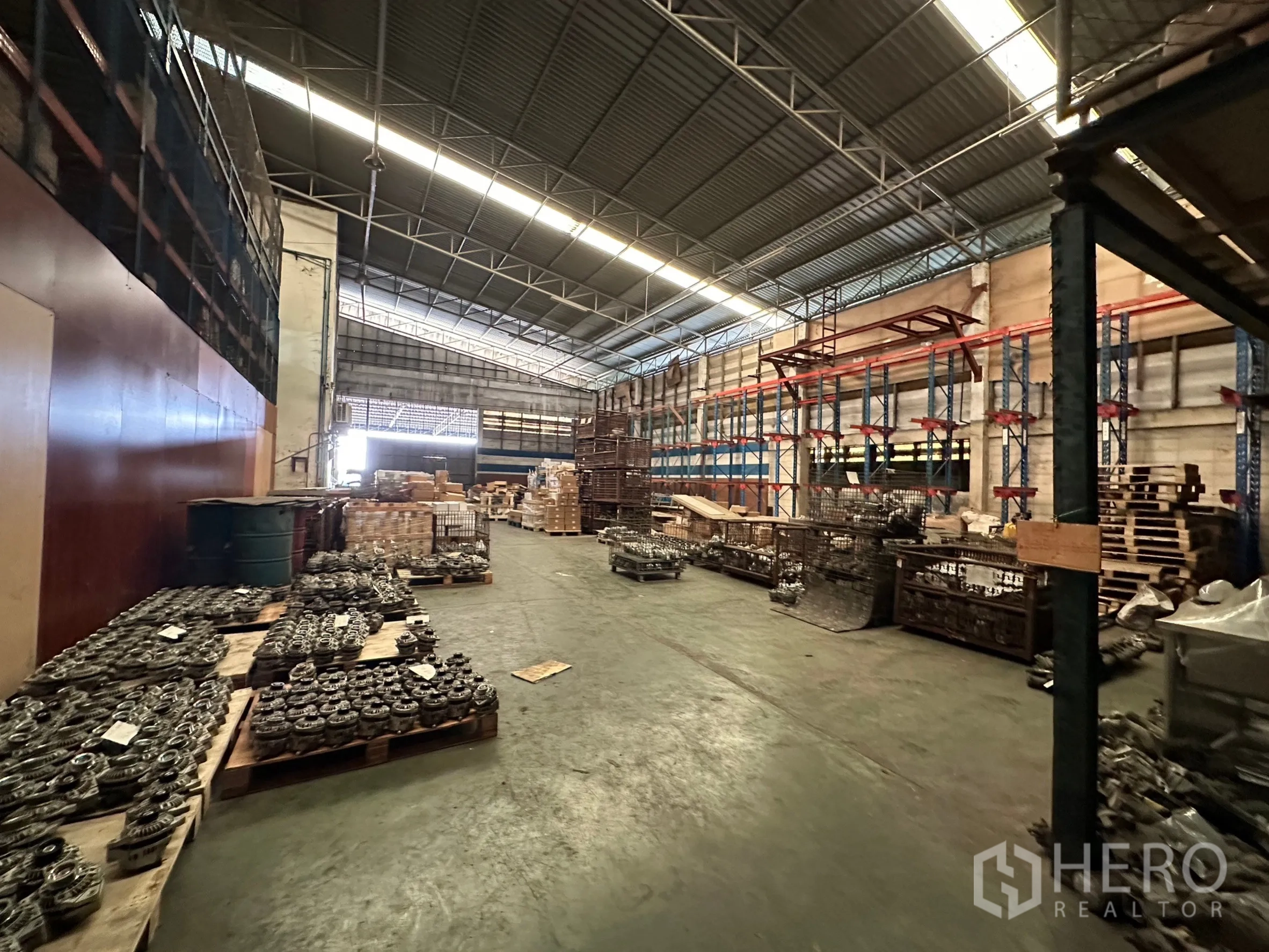 Factory for rent in Lam Luk Ka, Pathum Thani - Open floor warehouse bay with metal racks and materials on pallets.