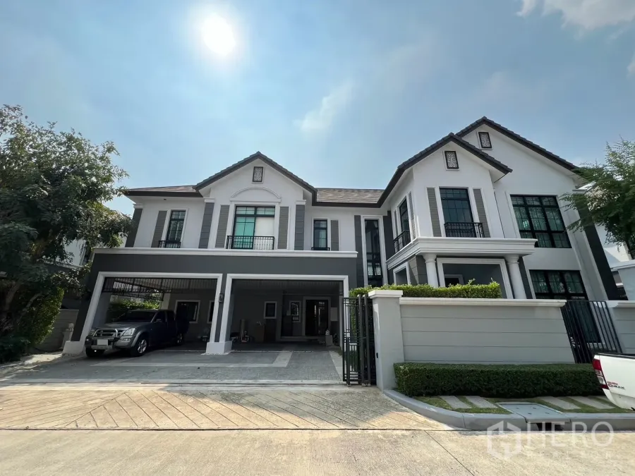 Detached House for rent or sale in Prawet, Bangkok - Grand two-storey detached house facade with gated driveway and two-car carport on a sunny day.