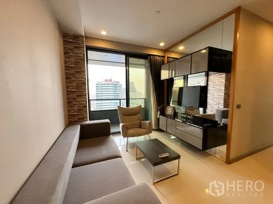 Condominium for rent in Bang Rak, Bangkok - Living area with sectional sofa, armchair and media console beside the balcony.