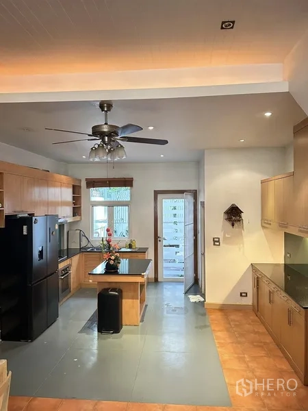 Townhouse for rent or sale in Khlong Toei, Bangkok - Family kitchen with central island, ceiling fan and door to the rear patio.
