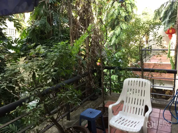 联排别墅 出租在Watthana, Bangkok - 被绿植环绕的上层阳台，配休闲椅与栏杆