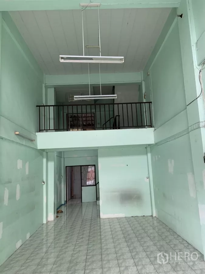 Shophouse for rent in Suan Luang, Bangkok - Double-height front hall with mezzanine and hanging fluorescent lights.