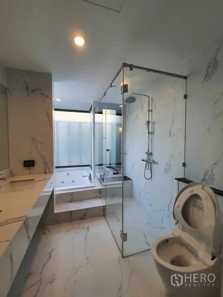Detached House for sale in Prawet, Bangkok - Luxurious bathroom with glass-enclosed shower, bathtub, and marble-effect walls.