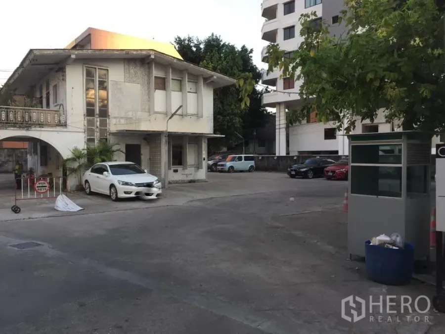Retail Space for rent in Khlong Toei, Bangkok - Two-storey building with archway and guard booth beside a large paved parking area near Thonglor.