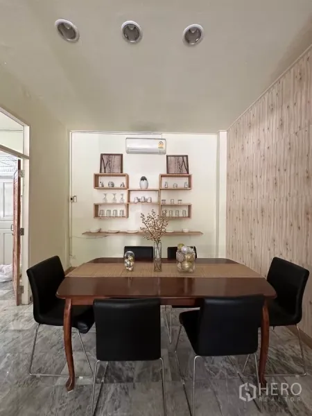 Home Office for rent in Suan Luang, Bangkok - Dining room with six chairs, wooden table, and wall-mounted shelves.