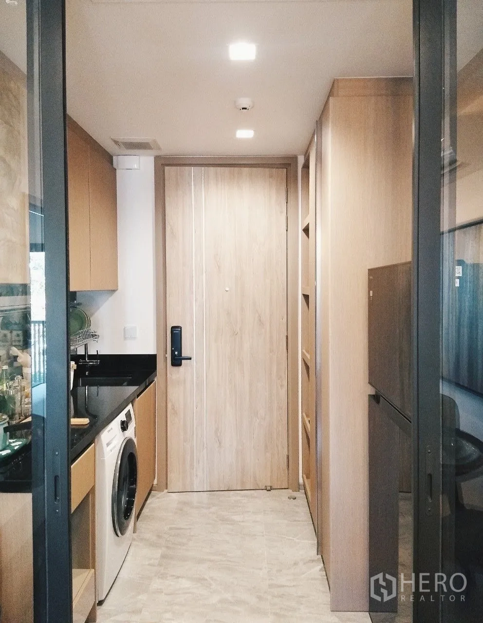Condominium for rent in Watthana, Bangkok - Separate kitchen corridor with black countertop, washing machine, and wood cabinetry.
