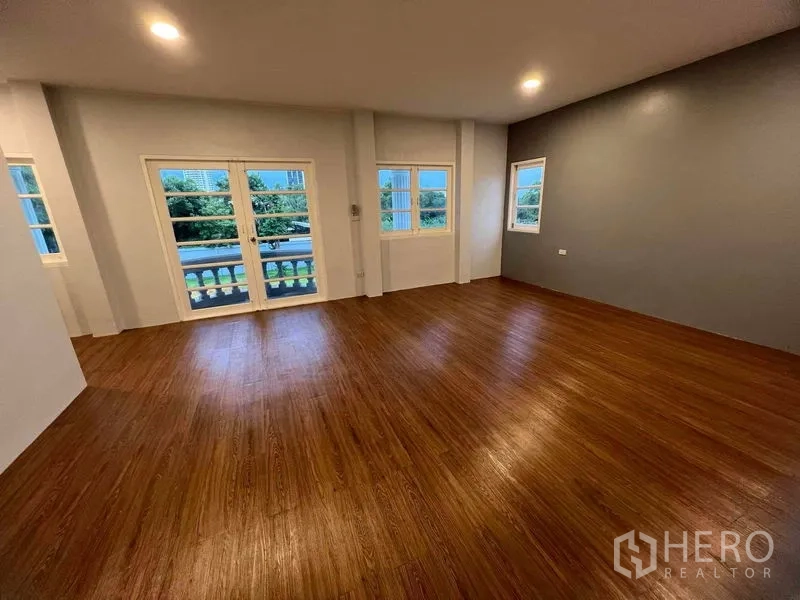 Detached House for sale in Bang Na, Bangkok - Spacious bedroom with wood flooring, balcony doors and multiple windows.