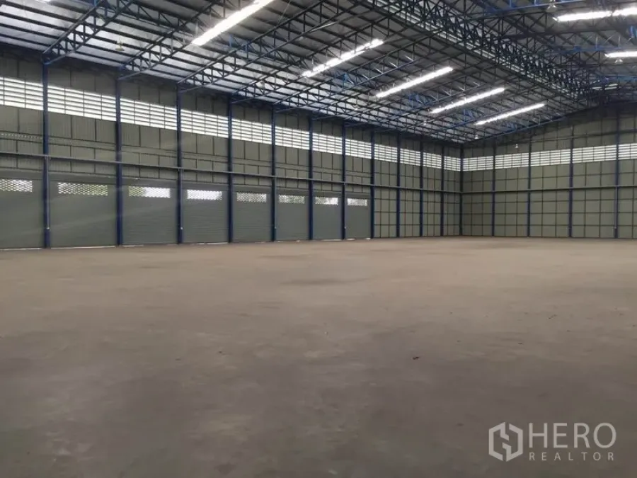Warehouse for rent in Pak Kret, Nonthaburi - Open warehouse hall showing multiple roller shutter doors and ventilated wall panels.