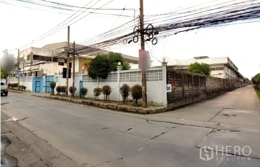 Factory for sale in Bang Phli, Samut Prakan - Street view of the walled factory compound with gate alongside the road.