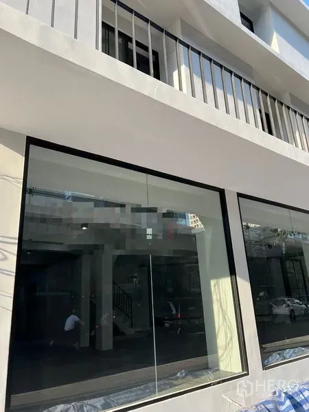 Shophouse for rent in Khlong Toei, Bangkok - Close-up of the shophouse’s ground-floor glass storefront and upper balcony railings.
