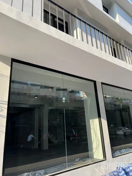 Shophouse for rent in Khlong Toei, Bangkok - Close-up of the shophouse’s ground-floor glass storefront and upper balcony railings.