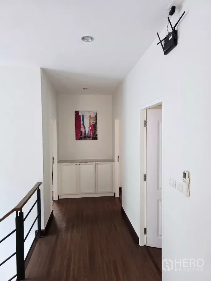 Detached House for rent in Prawet, Bangkok - Upper hallway with wood flooring, railings and storage cabinet.
