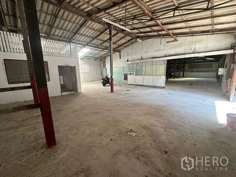 Warehouse for rent in Suan Luang, Bangkok - Open work area featuring partitioned office space, sliding gate access and red steel columns.