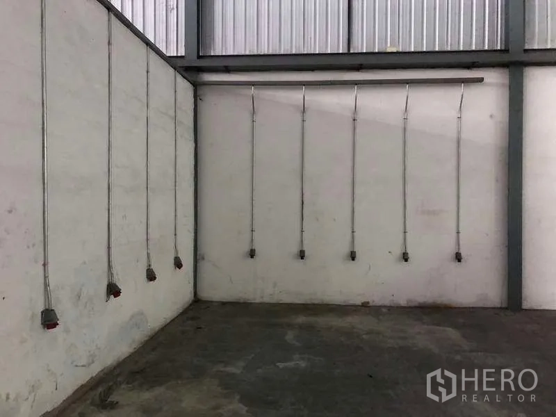 Warehouse for rent in Bang Phli, Samut Prakan - Industrial corner wall with multiple drop-down power outlets and metal conduits for machinery.