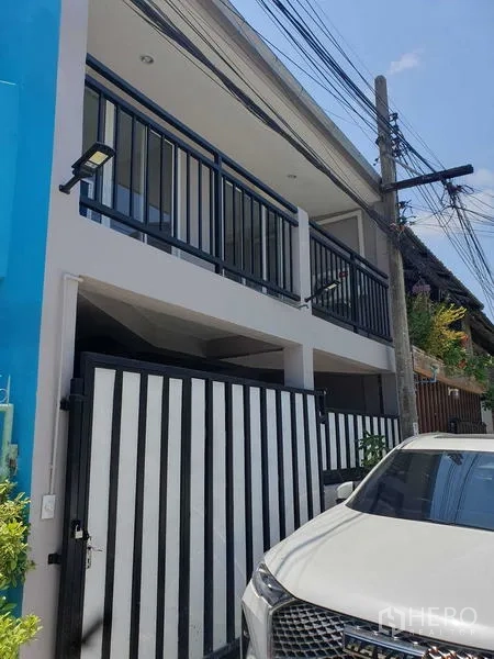 Home Office for rent in Suan Luang, Bangkok - Two-storey home office exterior with black metal gate, balcony railings and a street-side carport.