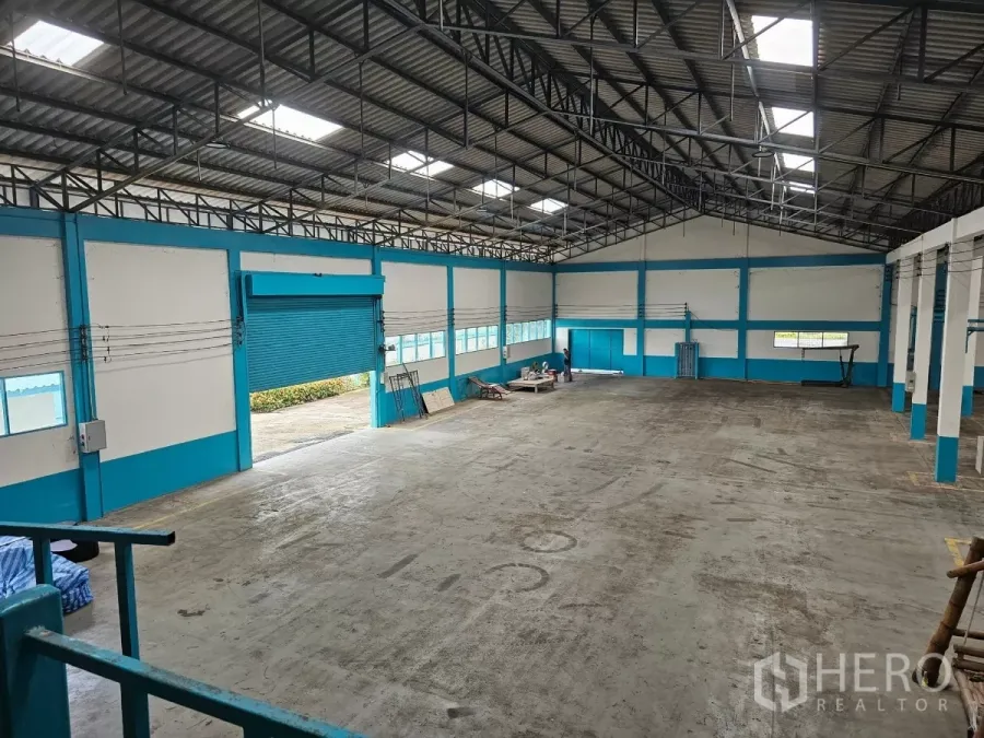 工厂 出租或出售在Mueang Rayong, Rayong - 工厂内部空间宽敞，钢梁高屋顶配采光板，重载混凝土地面与大型蓝色卷闸门。